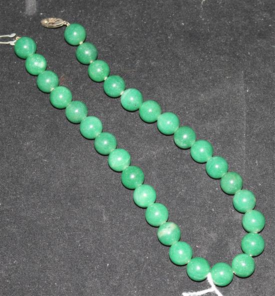 A necklace of thirty polished green jade beads, 14.25in.